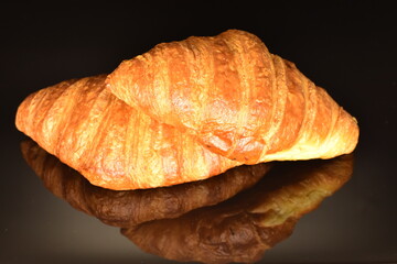 Fragrant homemade croissant, close-up, on a black background.