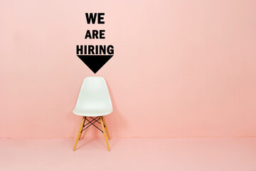 Job recruiting advertisement represented by 'WE ARE HIRING' texts on the wall. One chair to...