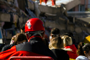 The back of the search and rescue worker blurred in front of the building destroyed in the...