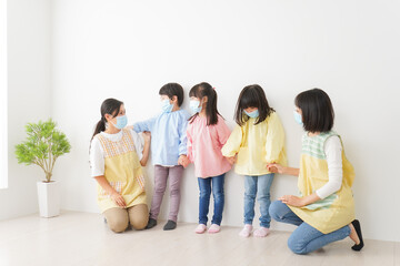 マスクを付けて幼稚園で遊ぶ子どもたちの先生