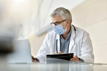 Portrait of doctor working in office with face mask