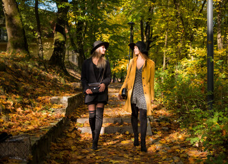 sesja fotograficzna w parku jesień dwie piękne białe kobiety dziewczyny w kapeluszach - obrazy, fototapety, plakaty