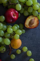 Colorful juicy fruits border.  Fresh summer fruits top view horizontal photo. Dark grey background with copy space. 