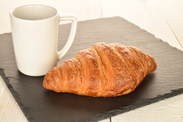 Fragrant homemade croissant, close-up, on a slate board.