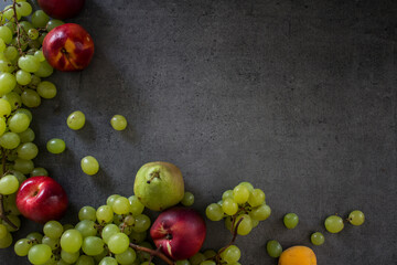 Beautiful fresh fruits on dark grey table: green grapes, nectarines, apricot. Summer fruits top view. 
