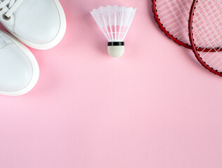 Sport flat lay with white sneakers , shuttlecock and two rackets for playing badminton on a pink background. Concept healthy lifestyle. Top view. Copy space. Banner. Place for text.