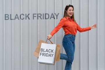 Black Friday concept, Woman holding many shopping bags walking with colorful shopping bags near the store during shopping process
