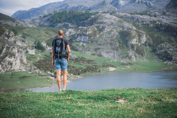 Photo from behind of a Backpacker man , on vacation. In the background beautiful landscape of Asturias.