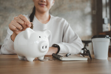 Happy smart asian woman saving money in a piggybank. saving and money concept.