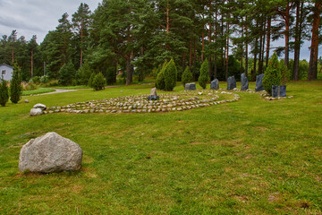 Glade for a magic ritual.In a clearing surrounded by coniferous trees, a magic labyrinth is laid out of stone. Grass grows on the field and stones lie. The sky is cloudy. Russia, nature, landscape