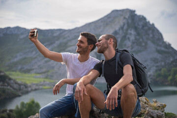 Two brothers, on vacation in the middle of nature, take a selfie. In the background the mountains and a lake in Asturias.