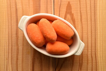 Ripe juicy organic mini carrots, close-up, on a  wooden table.