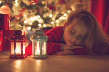 Happy Holidays. Cute little child near the Christmas tree. The girl laughs and enjoys Christmas. High quality photo.