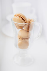 macarons in a coffee cup. caramel macaroons. Light flatley with dessert. Macaroni on white background. Cozy winter photography