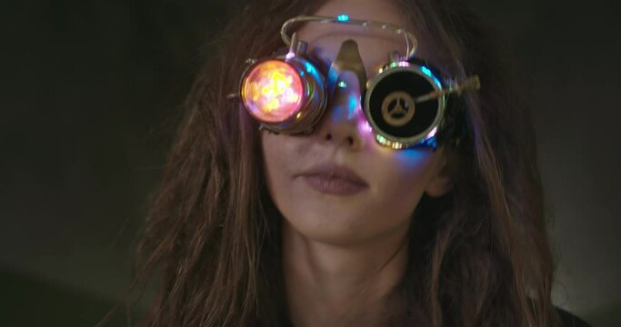 Woman in steampunk VR glasses experiencing virtual reality. Crazy female scientist with messy hair wearing glowing VR goggles and exploring virtual reality
