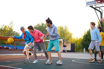 basketball players outdoors. summer vacation, holidays, games and friendship concept. caucasian teenagers in casual hoodies engaged in sport, healthy lifestyle, youth concept