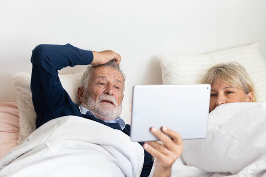 Senior couple using tablet on bed in bedroom