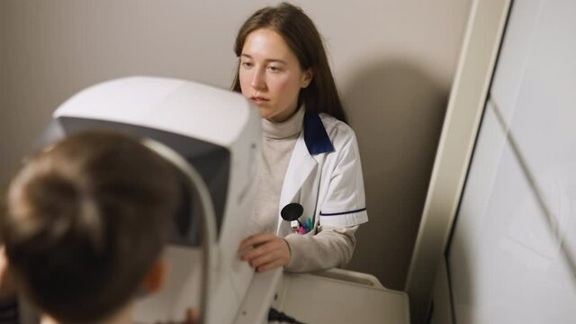 Young optometrist checks kid's vision using autorefractor