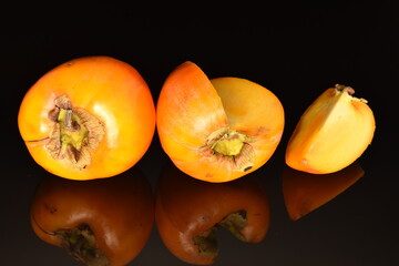 Ripe juicy organic persimmon, close-up, on a black background.