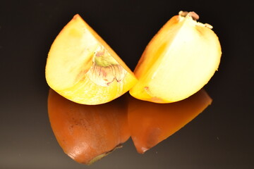 Ripe juicy organic persimmon, close-up, on a black background.