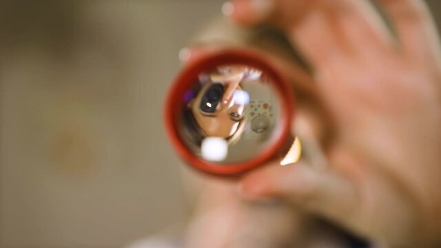 Young smiling eye doctor looks through lens blinking with ophthalmoscope