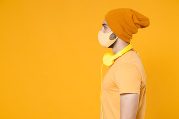 Side view of young man in basic casual t-shirt hat headphones face mask to safe from coronavirus...