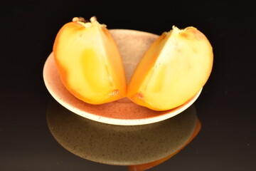 Fototapeta na wymiar Ripe juicy organic persimmon, close-up, on a black background.