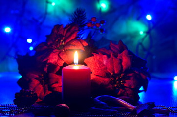 Christmas decorate with red colored candle by placing big red artificial flowers around it and...