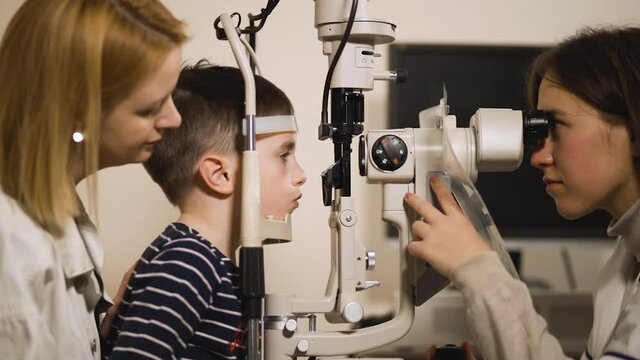 Optometrist checks kid's vision using modern opthalmology medical device