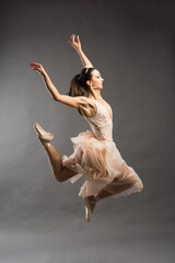 Beautiful ballet dancer posing on pointes on light grey studio background