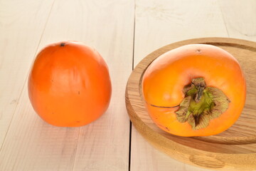 Ripe juicy organic persimmon, close-up, on a white wooden table.