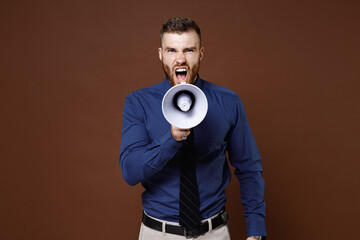 Angry irritated bearded young business man wearing blue shirt tie screaming in megaphone looking camera isolated on brown colour background studio portrait. Achievement career wealth business concept.