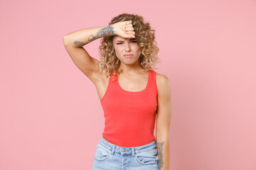 Exhausted tired displeased dissatisfied crying young blonde woman 20s wearing casual tank top standing put hand on head looking camera isolated on pastel pink colour wall background, studio portrait.