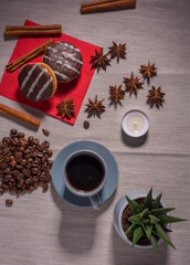 A cup of espresso is decorated with anise stars, cinnamon, sweets, dried lemons, acorns, peanuts in a beautiful dish.