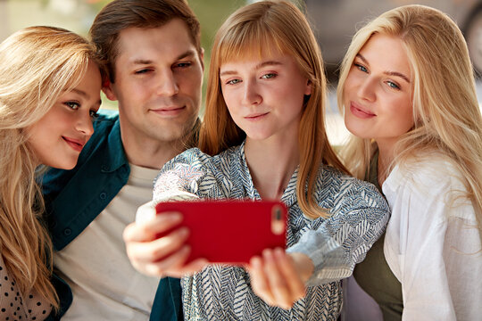 portrait of happy group of young caucasian friends taking photo on smartphone, smiling women and man spend time together in restaurant, gathered to share news, friendship concept