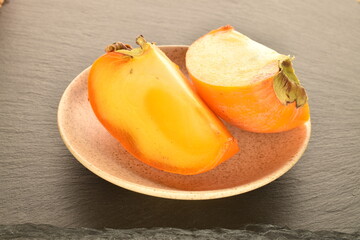 Ripe juicy organic persimmon, close-up, on a slate board.