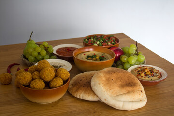 Traditional food of Israel on dark grey background with copy space. Colorful authentic meals top view photo: plate of hummus, falafels, salad, pita bread and tahini sauce. 