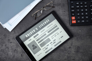 Tablet with driver's license application form, glasses and calculator on grey table, flat lay