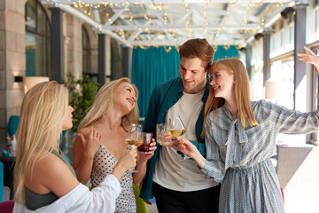 group of best friends having a great time in restaurant, celebrating birthday or corporate, they are chatting and drinking white wine