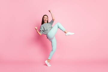 Full size photo of astonished funky young lady dancing wear shirt blue pants white sneakers isolated on pink color background