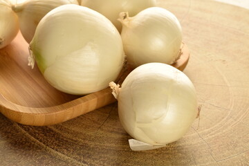 Ripe white organic onions, close-up, on a wooden table.