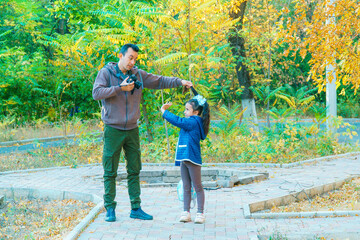 Father and daughter walk in the park and take pictures. Daughter doesn't want to pose