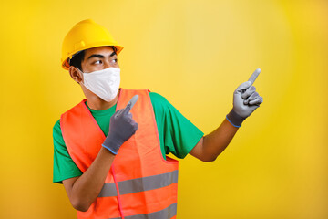 Asian construction worker wearing protective mask pointing isomething in his side