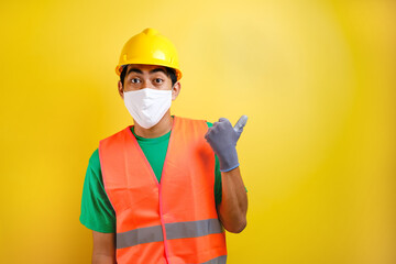 Asian construction worker wearing protective mask pointing isomething in his side