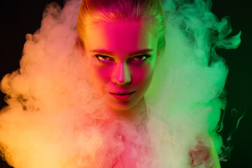 Passioned. Portrait of female fashion model in neon light on dark studio background with smoke. Beautiful caucasian woman with trendy make-up and well-kept skin. Vivid style, beauty concept. Close up.