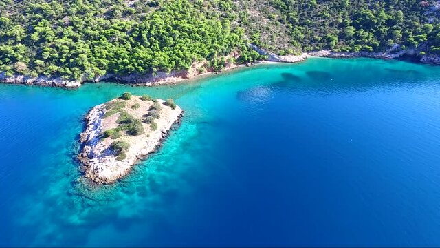 Aerial view of Siderona bay, Corinthia, Greece, on a lovely bright day in a calm blue and turquoise sea, with sailing boat