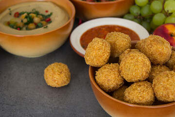 Traditional food of Israel on dark grey background with copy space. Colorful authentic meals top view photo: plate of hummus, falafels, salad, pita bread and tahini sauce. 