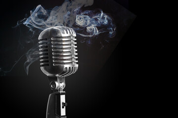 A microphone has smoke around it on black background for a music or entertainment concept.