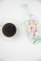 Fototapeta na wymiar White coconut candy balls on handmade upcycle plate from the bottle. Coconut cookies on white background with the cup of tea. Teapot with black tea. 