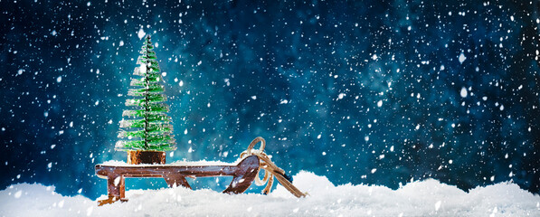 Small Christmas tree on wooden sled or sleigh, New Year snowy background, Xmas concept